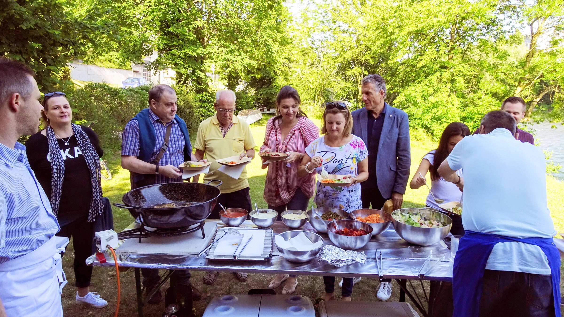 Clubmitglieder kochen im Freien und richten das Buffet an